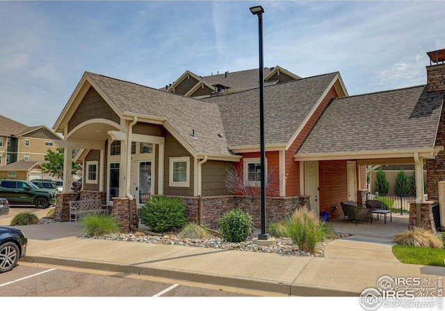 4642 Hahns Peak Dr Unit 101, Loveland, CO 80538 - view of front of property featuring a porch, stone siding, and roof with shingles
