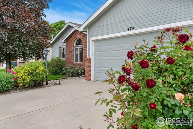 474 Radiant Dr, Loveland, CO 80538 - view of front of home featuring driveway, brick siding, and an attached garage