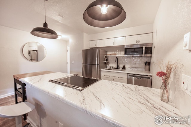 2636 Juniper Ave Unit 39-2, Boulder, CO 80304 - kitchen with stainless steel appliances, a sink, white cabinetry, decorative backsplash, and a kitchen bar