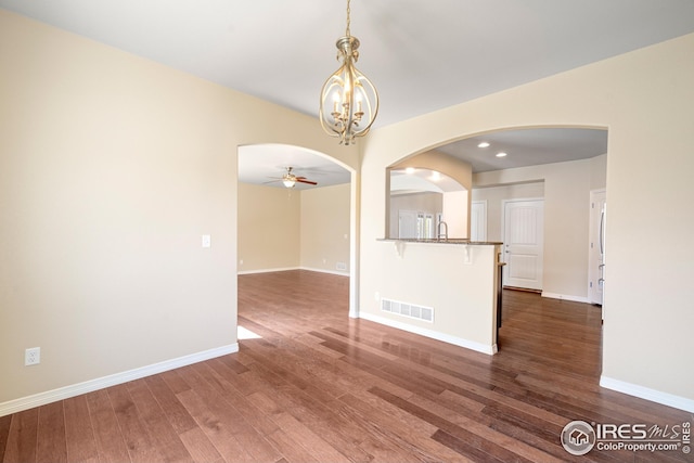 848 Shirttail Peak Dr, Windsor, CO 80550 - spare room with dark wood-type flooring, a ceiling fan, arched walkways, baseboards, and a chandelier