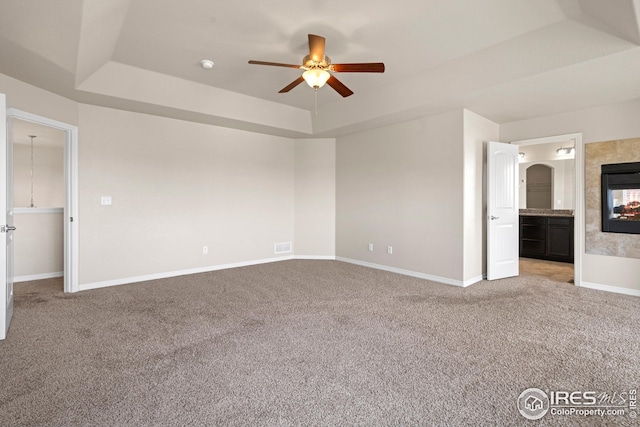 848 Shirttail Peak Dr, Windsor, CO 80550 - carpeted empty room with a tray ceiling, ceiling fan, a tile fireplace, and baseboards