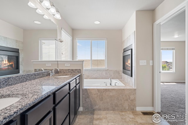 848 Shirttail Peak Dr, Windsor, CO 80550 - full bath with a glass covered fireplace, a bath, plenty of natural light, and double vanity