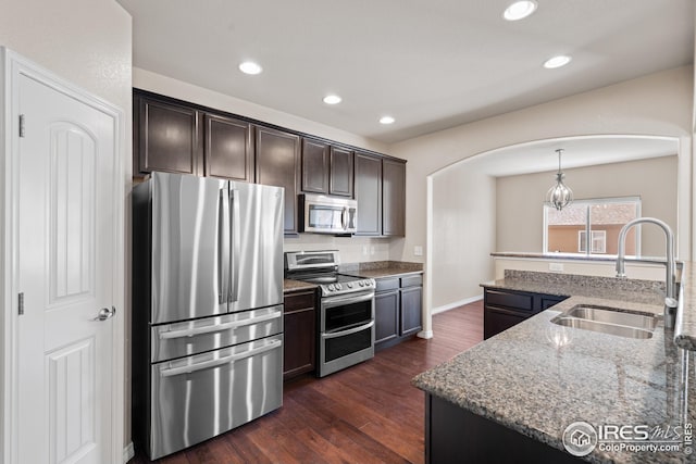848 Shirttail Peak Dr, Windsor, CO 80550 - kitchen with appliances with stainless steel finishes, a sink, arched walkways, light stone counters, and recessed lighting