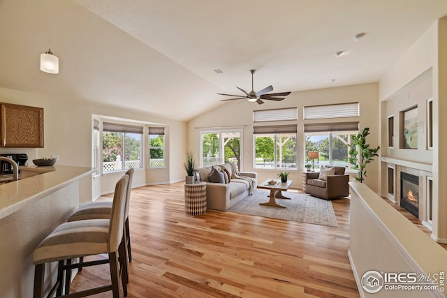 1427 Reeves Dr, Fort Collins, CO 80526 - living room with light wood finished floors, ceiling fan, a tiled fireplace, and lofted ceiling