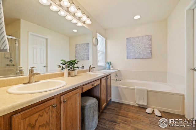 1427 Reeves Dr, Fort Collins, CO 80526 - bathroom with a bath, double vanity, a shower stall, wood finished floors, and recessed lighting