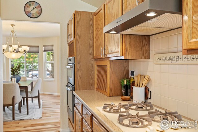 1427 Reeves Dr, Fort Collins, CO 80526 - kitchen featuring ventilation hood, white gas stovetop, a chandelier, light wood-type flooring, and brown cabinets