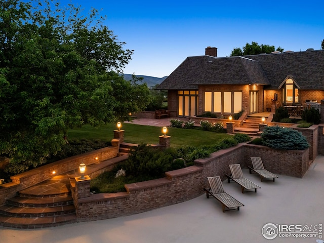 8000 N 41st St, Longmont, CO 80503 - rear view of house featuring a patio area, an outdoor fire pit, a chimney, a yard, and brick siding