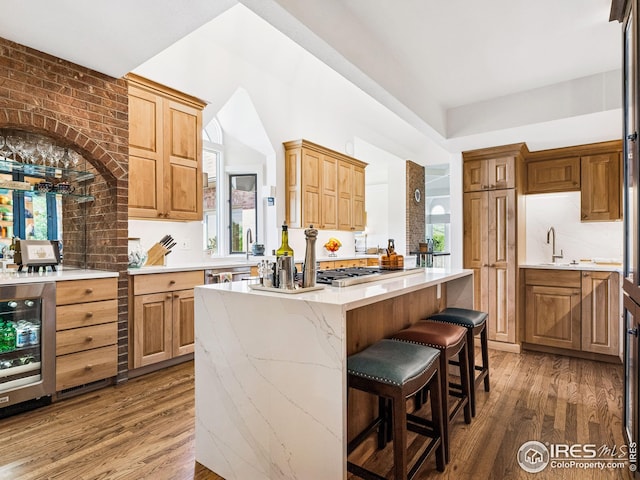 8000 N 41st St, Longmont, CO 80503 - kitchen with wood finished floors, a kitchen island, stainless steel gas stovetop, wine cooler, and a kitchen bar