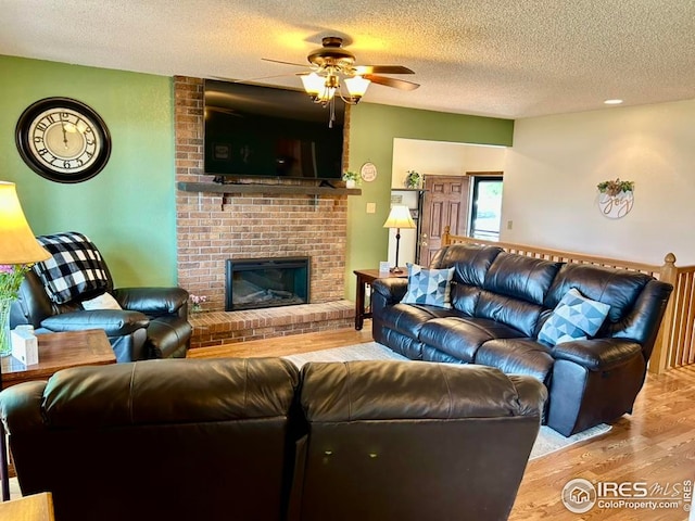 1722 Pheasant Rdg, Sterling, CO 80751 - living room featuring ceiling fan, wood finished floors, a textured ceiling, and a brick fireplace