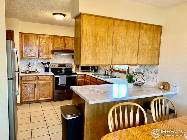 1722 Pheasant Rdg, Sterling, CO 80751 - kitchen featuring stainless steel appliances, a peninsula, a sink, under cabinet range hood, and light countertops