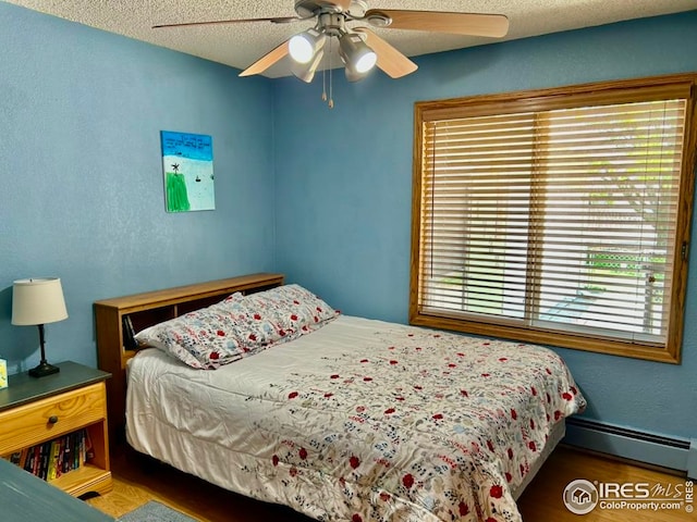 1722 Pheasant Rdg, Sterling, CO 80751 - bedroom with baseboard heating, wood finished floors, a ceiling fan, and a textured ceiling