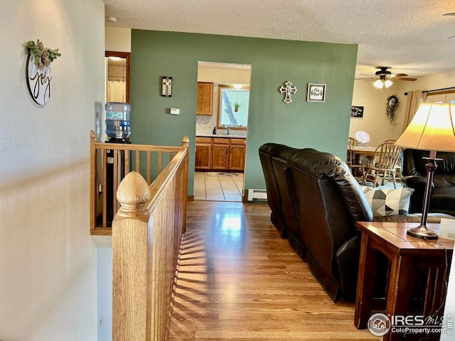 1722 Pheasant Rdg, Sterling, CO 80751 - living room featuring light wood-type flooring, baseboard heating, ceiling fan, and a textured ceiling