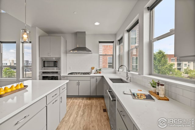 9052 E 47th Ave, Denver, CO 80238 - kitchen with wall chimney exhaust hood, gray cabinets, appliances with stainless steel finishes, healthy amount of natural light, and recessed lighting