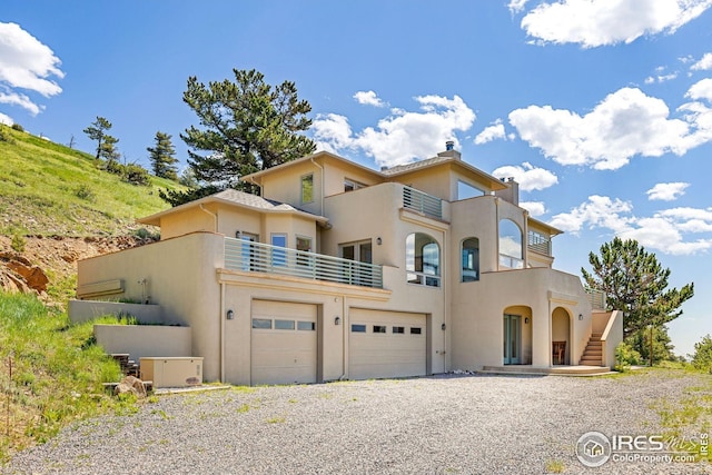 606 Sugarloaf Mountain Rd, Boulder, CO 80302 - view of front facade with a balcony, a garage, stucco siding, a chimney, and gravel driveway