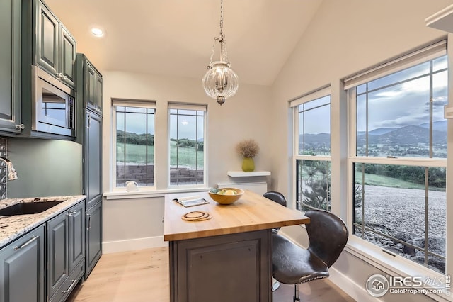 1570 County Road 37e, Lyons, CO 80540 - kitchen featuring wood counters, light wood-type flooring, a kitchen breakfast bar, a mountain view, and vaulted ceiling