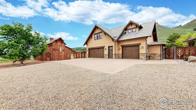 1570 County Road 37e, Lyons, CO 80540 - view of front of property with stone siding, a barn, driveway, stucco siding, and a garage