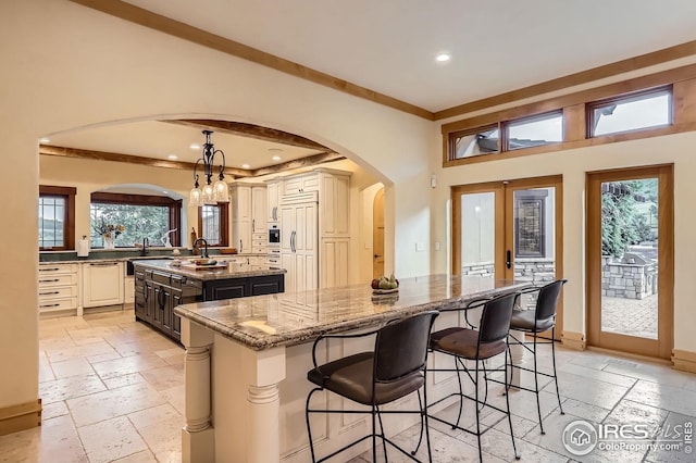 1570 County Road 37e, Lyons, CO 80540 - kitchen featuring arched walkways, a kitchen island, stone tile flooring, recessed lighting, and light stone counters