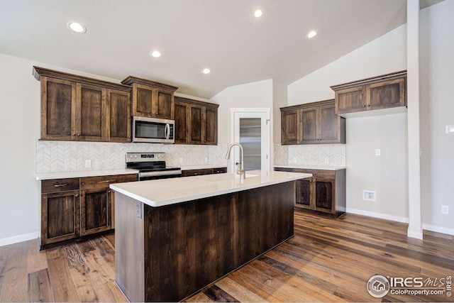7150 Rye Grass Dr, Wellington, CO 80549 - kitchen featuring stainless steel appliances, vaulted ceiling, decorative backsplash, dark brown cabinetry, and recessed lighting