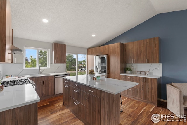 2037 Spencer St, Longmont, CO 80501 - kitchen featuring appliances with stainless steel finishes, vaulted ceiling, a textured ceiling, a kitchen island, and dark wood-style floors