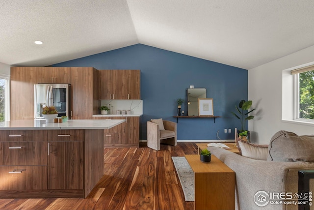 2037 Spencer St, Longmont, CO 80501 - kitchen featuring stainless steel fridge, lofted ceiling, brown cabinetry, dark wood-style floors, and light countertops