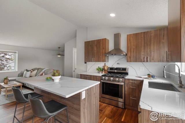 2037 Spencer St, Longmont, CO 80501 - kitchen featuring gas range, wall chimney range hood, modern cabinets, vaulted ceiling, and brown cabinets