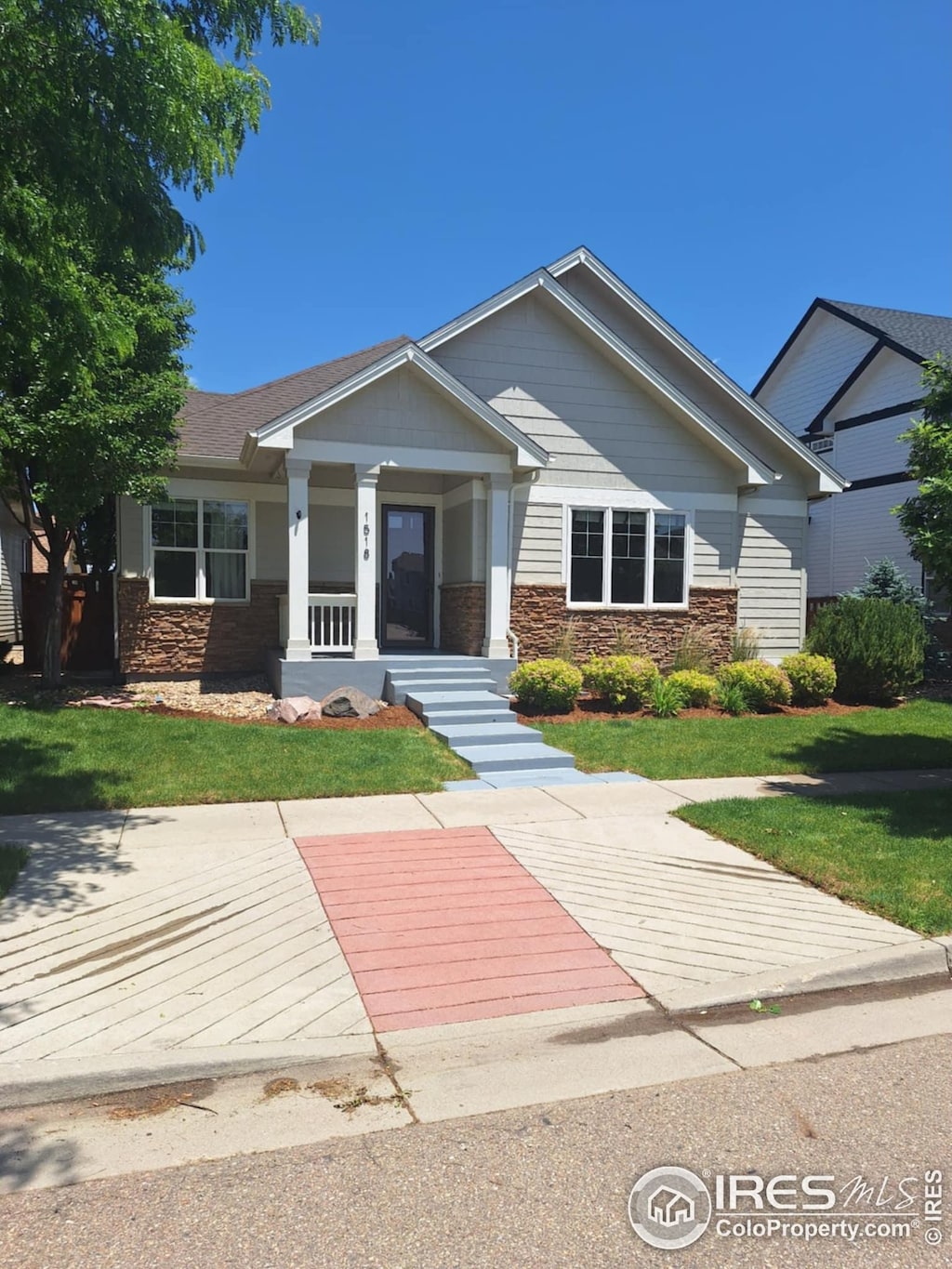 1518 Hollyberry St, Berthoud, CO 80513 - view of front of property with stone siding, a front lawn, and a porch