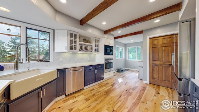 2029 Uplands Cir, Estes Park, CO 80517 - kitchen featuring appliances with stainless steel finishes, white cabinetry, light wood-type flooring, beamed ceiling, and backsplash