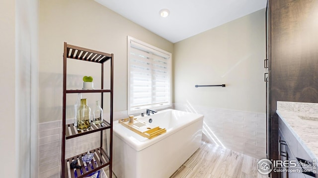 2029 Uplands Cir, Estes Park, CO 80517 - bathroom featuring a freestanding bath, tile walls, vanity, and a wainscoted wall