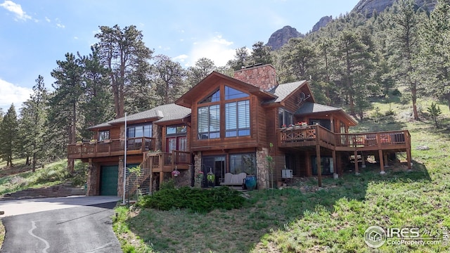 2029 Uplands Cir, Estes Park, CO 80517 - view of front of home featuring a deck with mountain view, driveway, a garage, and stone siding