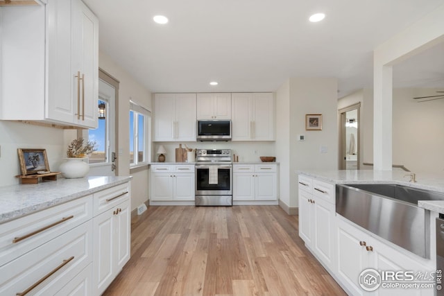 34288 County Road 59, Gill, CO 80624 - kitchen featuring appliances with stainless steel finishes, white cabinets, light wood-style floors, recessed lighting, and light stone countertops