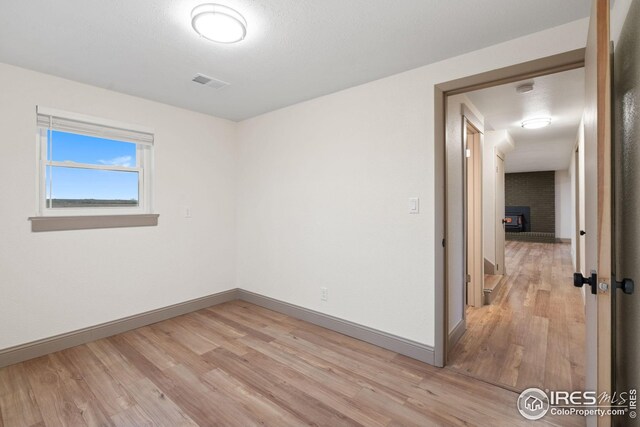 34288 County Road 59, Gill, CO 80624 - spare room featuring light wood-style flooring, a brick fireplace, and a smoke detector