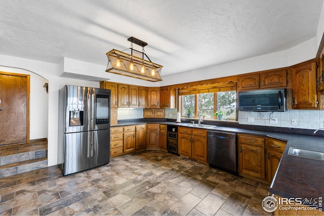 14975 US Highway 385, Julesburg, CO 80737 - kitchen with appliances with stainless steel finishes, dark countertops, brown cabinets, decorative backsplash, and stone finish flooring