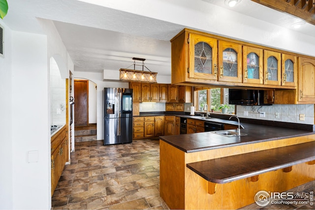 14975 US Highway 385, Julesburg, CO 80737 - kitchen with refrigerator with ice dispenser, arched walkways, dark countertops, a peninsula, and brown cabinetry