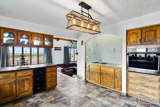 14975 US Highway 385, Julesburg, CO 80737 - kitchen with oven, wine cooler, gas cooktop, brown cabinets, and decorative light fixtures