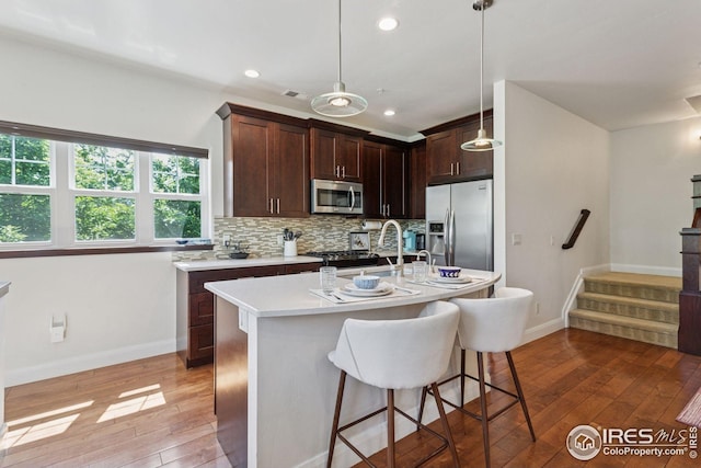 1944 Arapahoe Ave Unit A, Boulder, CO 80302 - kitchen with stainless steel appliances, light wood finished floors, light countertops, a breakfast bar, and backsplash