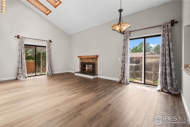 7414 Benton St, Arvada, CO 80003 - unfurnished living room featuring high vaulted ceiling, plenty of natural light, a glass covered fireplace, a skylight, and wood finished floors