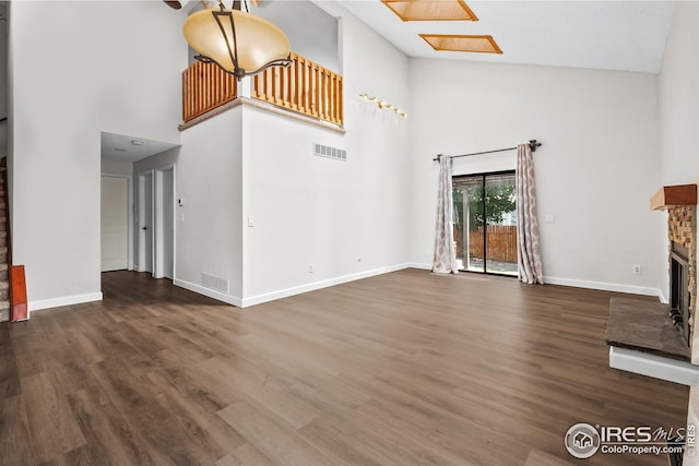 7414 Benton St, Arvada, CO 80003 - unfurnished living room featuring a fireplace with raised hearth, high vaulted ceiling, and wood finished floors