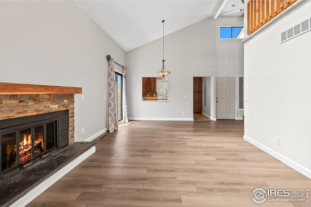 7414 Benton St, Arvada, CO 80003 - unfurnished living room with high vaulted ceiling, a glass covered fireplace, and light wood-style flooring