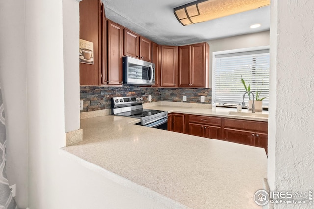 7414 Benton St, Arvada, CO 80003 - kitchen featuring stainless steel appliances, tasteful backsplash, light countertops, and brown cabinets