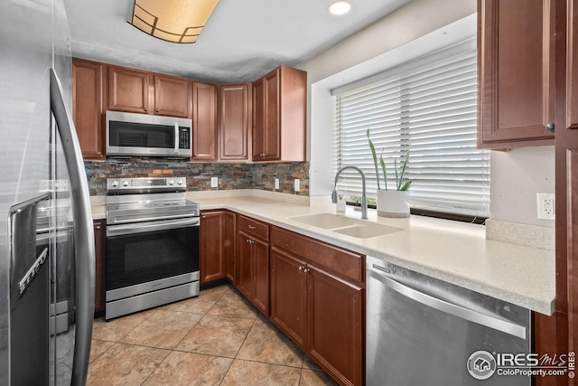 7414 Benton St, Arvada, CO 80003 - kitchen with stainless steel appliances, light countertops, decorative backsplash, and brown cabinets