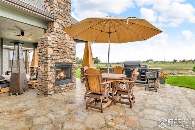37021 Kingfisher Ct, Severance, CO 80550 - view of patio / terrace featuring an outdoor stone fireplace, outdoor dining space, grilling area, and a ceiling fan