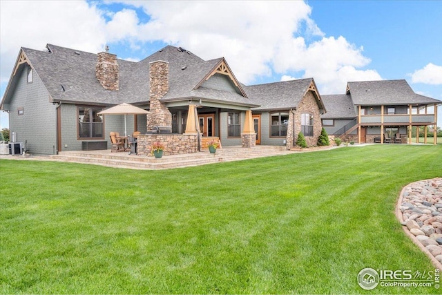 37021 Kingfisher Ct, Severance, CO 80550 - rear view of house featuring a chimney, a patio area, a yard, a shingled roof, and stone siding