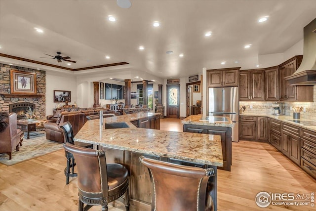 37021 Kingfisher Ct, Severance, CO 80550 - kitchen with freestanding refrigerator, a large island with sink, ceiling fan, tasteful backsplash, and recessed lighting