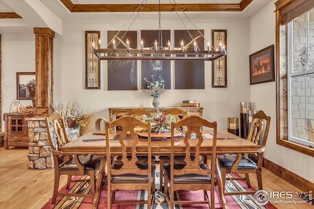 37021 Kingfisher Ct, Severance, CO 80550 - dining area featuring a chandelier, wood finished floors, and decorative columns