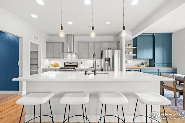 415 Stout St, Fort Collins, CO 80524 - kitchen with wall chimney range hood, stainless steel appliances, light countertops, a kitchen bar, and recessed lighting