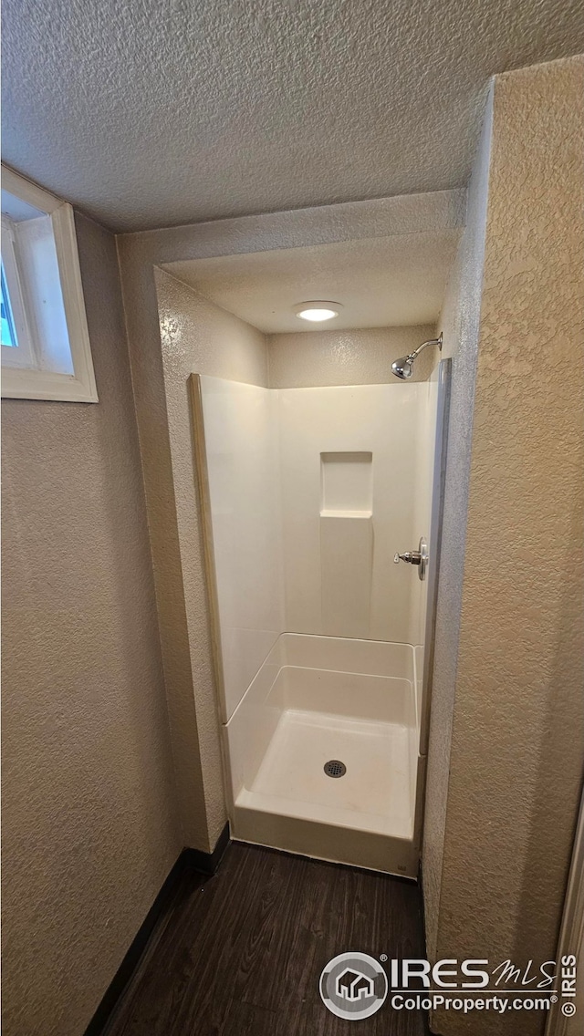 351 E 2nd St, Akron, CO 80720 - full bath featuring a textured wall, wood finished floors, a textured ceiling, and a stall shower