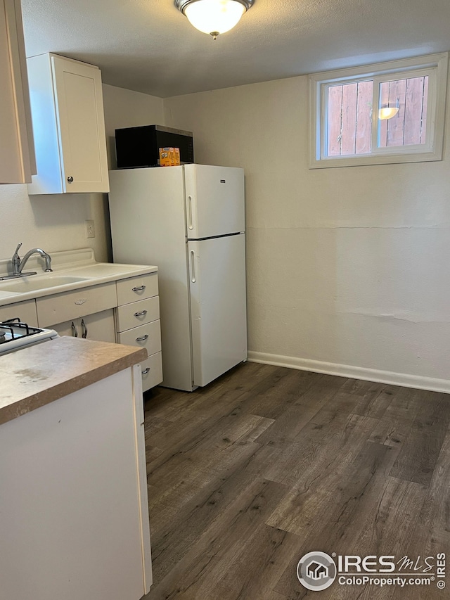 351 E 2nd St, Akron, CO 80720 - kitchen with freestanding refrigerator, white cabinetry, dark wood-style flooring, and light countertops