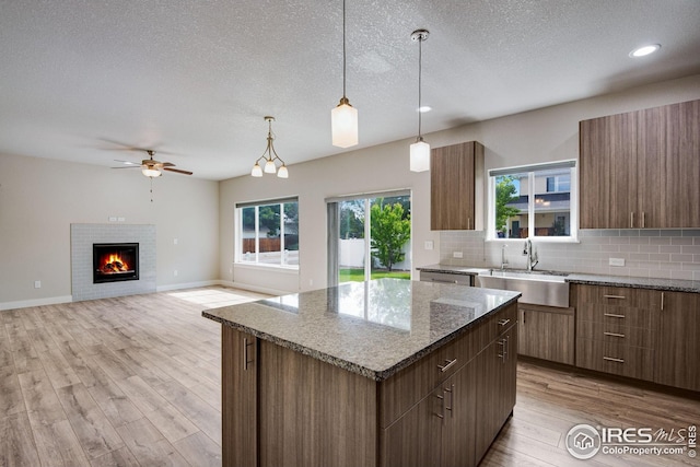 108 Wake St, Frederick, CO 80530 - kitchen featuring a kitchen island, backsplash, light wood-style flooring, ceiling fan, and a textured ceiling