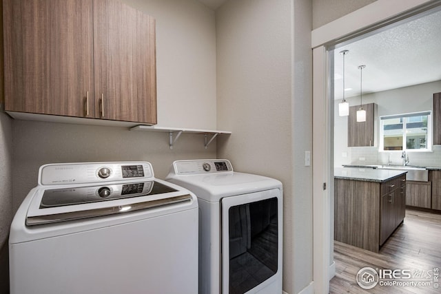 108 Wake St, Frederick, CO 80530 - laundry area featuring independent washer and dryer, light wood finished floors, and cabinet space