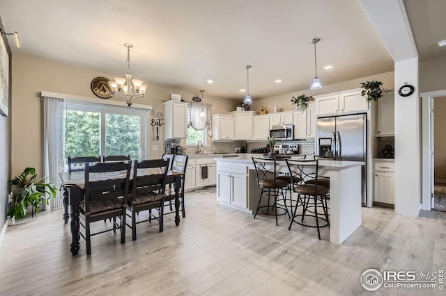 7840 Cattail Grn, Frederick, CO 80530 - kitchen featuring appliances with stainless steel finishes, backsplash, white cabinets, a kitchen island, and recessed lighting